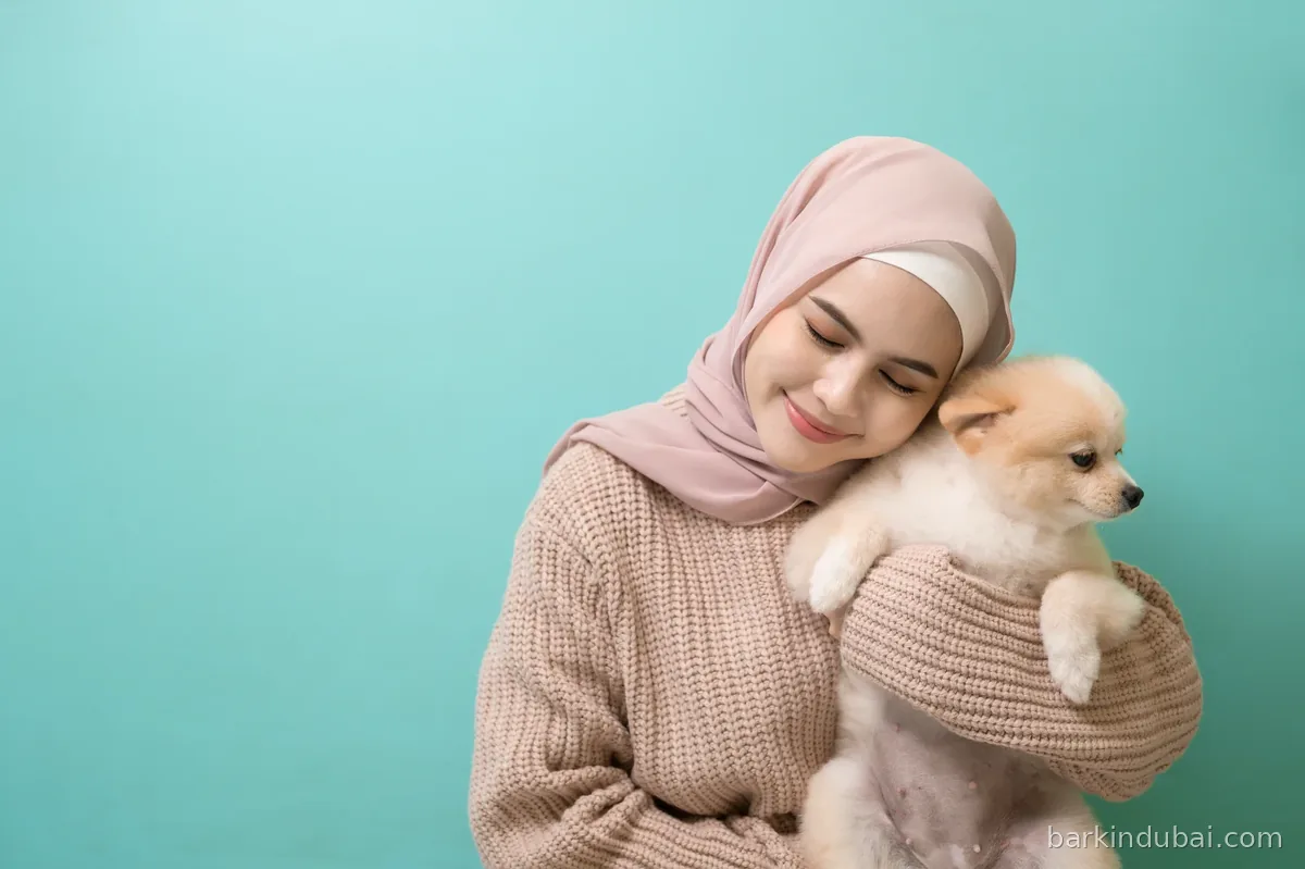 Woman holding a small dog against a teal background